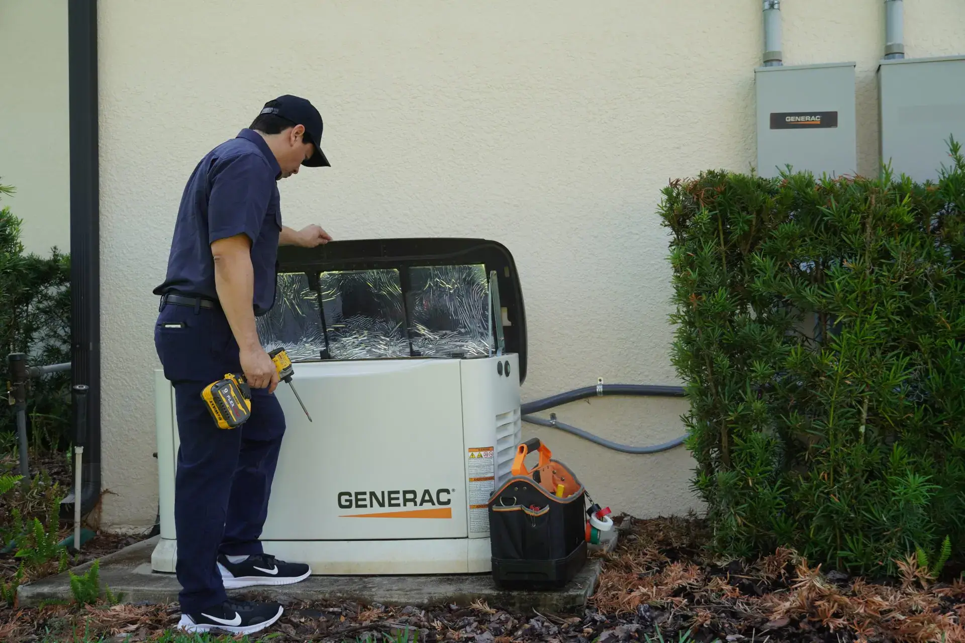 Electrician working on a Generac standby generator with a drill, emphasizing backup power installation.